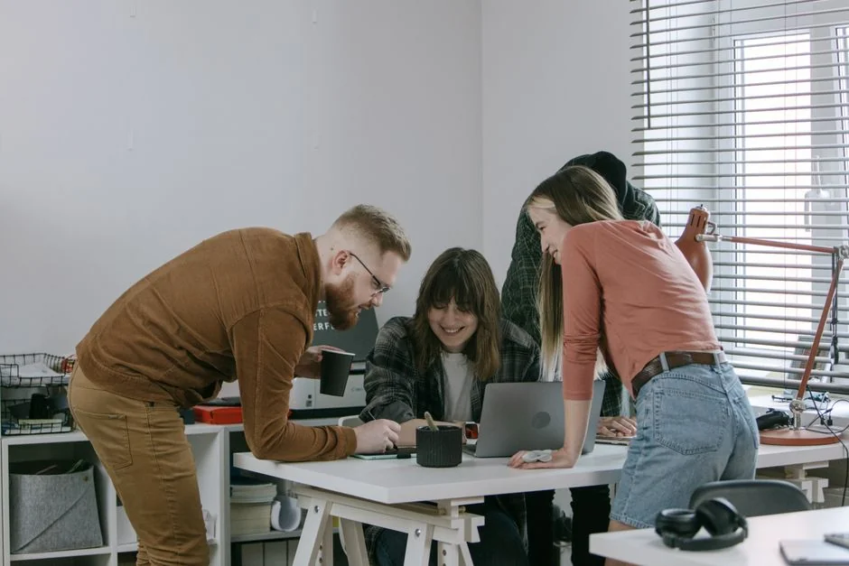 A photographer working at a creative setup with a laptop and Wacom tablet, focused on editing photos indoors.